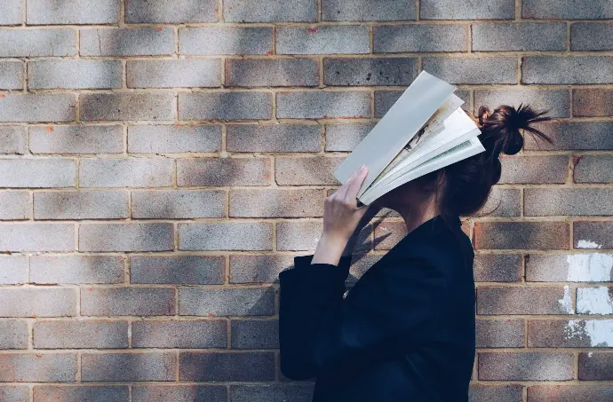 woman covering her face with white book